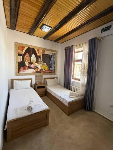 a bedroom with two beds and a painting on the wall at Afsona guest house in Bukhara