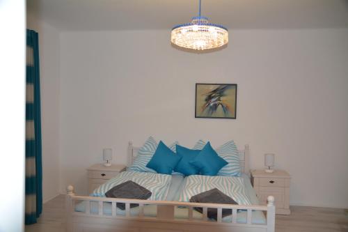 a bedroom with a bed with blue pillows and a chandelier at Haus 4 you in Winden am See