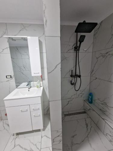 a white bathroom with a sink and a shower at Cazare Ineu 2 in Ineu