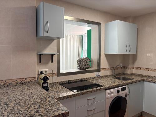 a kitchen with white cabinets and a sink and a mirror at The Bajondillo terrace in Torremolinos