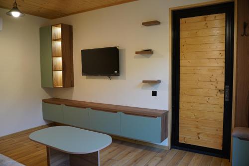 a living room with a tv and a table and a door at ნეტარა in Khizabavra