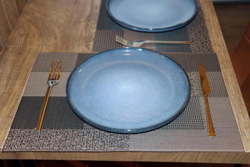two blue plates and forks on a wooden table at Superior Petit Studio in Mytilini
