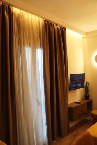 a room with a window with curtains and a television at Superior Petit Studio in Mytilini