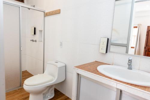 a white bathroom with a toilet and a sink at Costa Beach in Zorritos