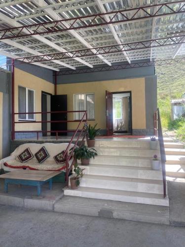 a house with stairs and a couch in front of it at Taldy-Bulak Guest House in Barskoon