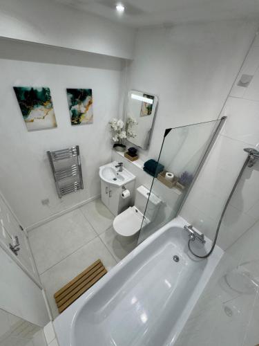a white bathroom with a tub and a toilet at Cozy one bedroom apartment in Surbiton