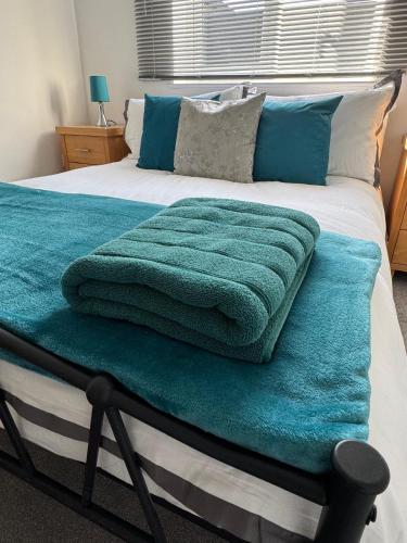 a bed with a green blanket on top of it at Cozy one bedroom apartment in Surbiton