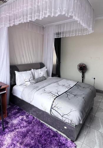 a bedroom with a large bed with a purple rug at CTS Suites in Kampala
