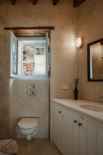 a bathroom with a toilet and a sink and a window at MAZAS House in Kámbos
