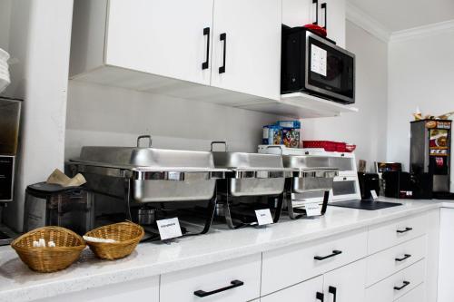 a kitchen with two sinks and a microwave at Ramada by Wyndham Sherwood Park in Sherwood Park