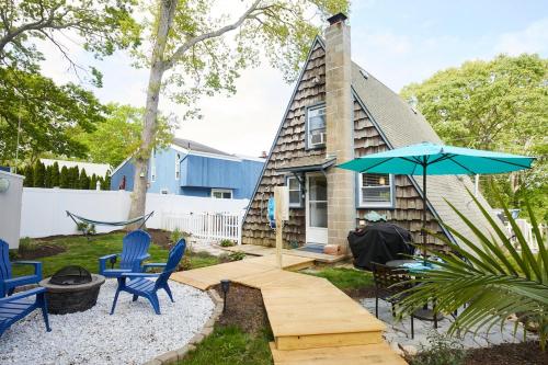 Una pequeña casa con sillas azules y una sombrilla. en Your Nest Near The Beach, en Giants Neck