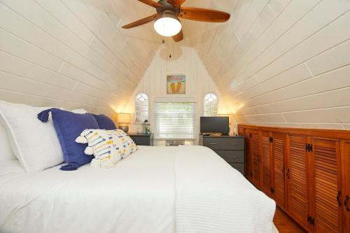 Un dormitorio con una cama blanca con ventilador de techo. en Your Nest Near The Beach, en Giants Neck