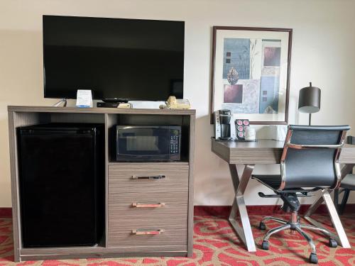 a desk with a microwave and a desk with a television at Ramada by Wyndham Sherwood Park in Sherwood Park