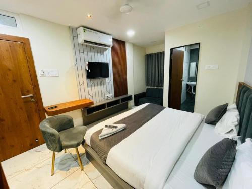 a bedroom with a bed and a chair and a television at Hotel Namaste in Indore