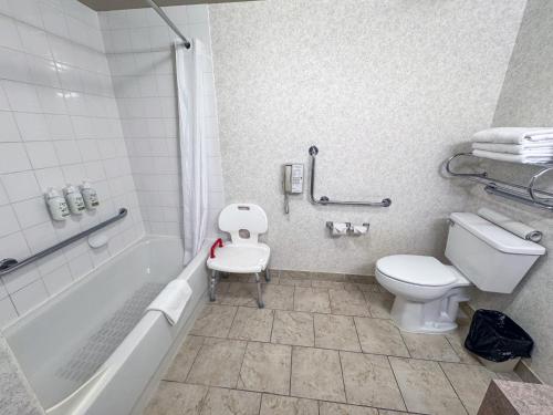 a bathroom with a toilet and a tub and a sink at Ramada by Wyndham Sherwood Park in Sherwood Park