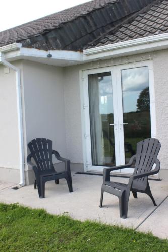 two chairs sitting on a patio in front of a house at Family Home, 20 mins from Youghal Beach in Killeagh