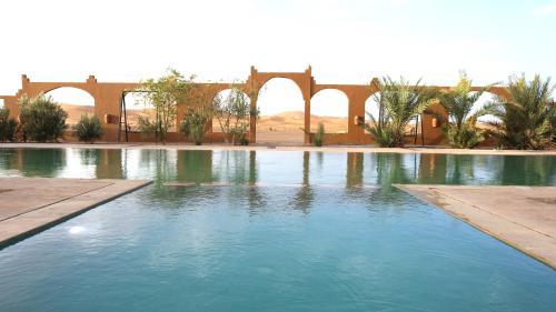 a large pool of blue water in a courtyard at Kasbah Du Berger & Piscine in Merzouga