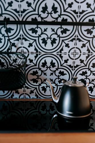 a black tea kettle sitting on a table with a black and white wallpaper at Chata Pod Lasem in Poręba