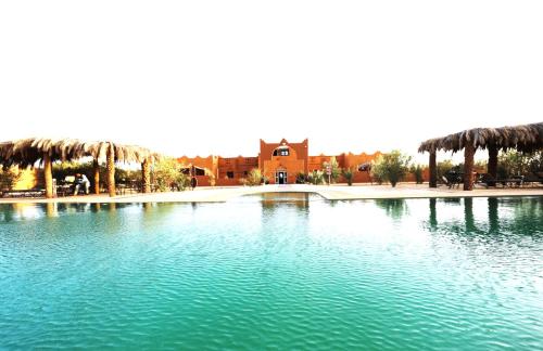 a large pool of water with a building in the background at Kasbah Du Berger & Piscine in Merzouga