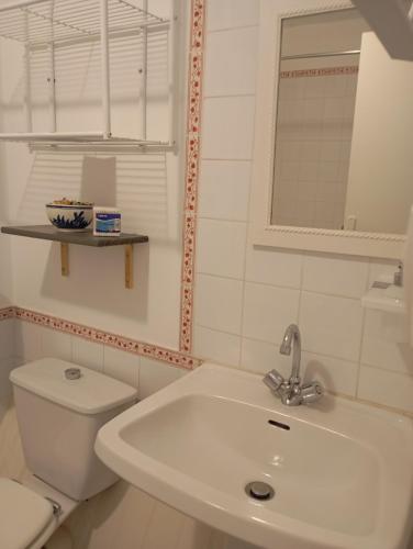 a white bathroom with a toilet and a sink at La chaise in Saint-Aquilin