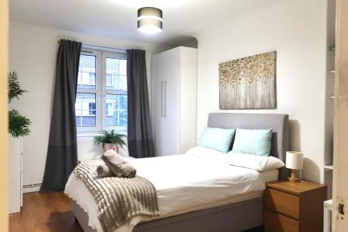 a bedroom with a large white bed and a window at Stylish 3-bed apartment in London within walking distance to tube stations in London