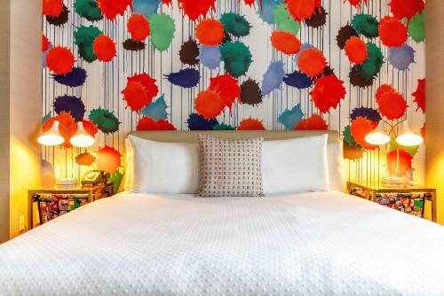 a bedroom with a white bed and a colorful wall at The Kinney - Venice Beach in Los Angeles