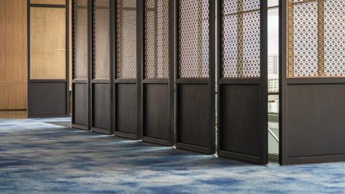 a row of stalls in a room with blue carpet at Crowne Plaza Penang Straits City by IHG in Perai
