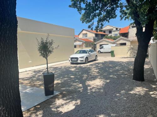 a white car parked in a parking lot with a tree at Luxury Villa Olga in Biograd na Moru