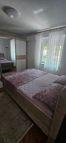 a large bed in a room with two windows at Olive Roots Yard House in Trebinje