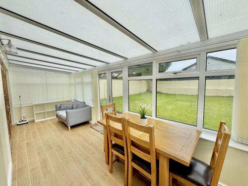 a living room with a table and chairs and windows at Trehwfa in Holyhead