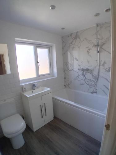 a bathroom with a tub and a toilet and a sink at "Woodbrook" 2 Bedroom House in Whaley Bridge