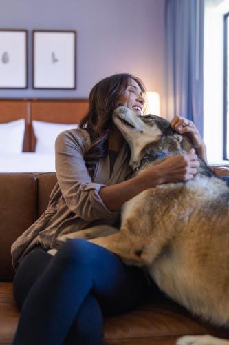 a woman sitting on a couch with a dog at Martis Valley Lodge, Tapestry Collection by Hilton in Truckee