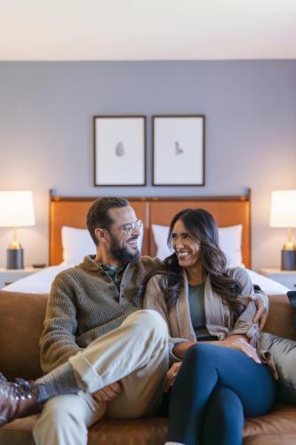 a man and a woman sitting on a bed at Martis Valley Lodge, Tapestry Collection by Hilton in Truckee