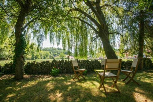 two chairs and a table under a tree at Posada La Fuentona de Ruente in Ruente