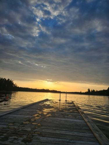 a dock on a lake with the sun setting at Sjönära villa in Oskarshamn