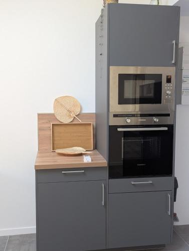 une cuisine avec un comptoir avec un micro-ondes et une cuisinière dans l'établissement Studio des Pins, à Hourtin
