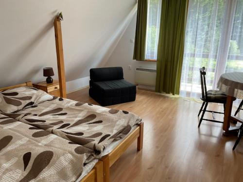 a bedroom with a bed and a chair and window at Domek u Pawła in Piwniczna