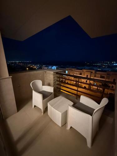 a balcony with white chairs and a view of a city at Luxury Apprt 2 ch ,prestigia des nations in Sidi Bouqnadel