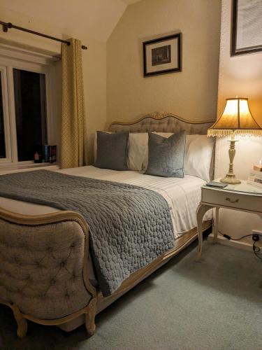 a bedroom with a bed and a table with a lamp at Lydgate House Hotel in Postbridge