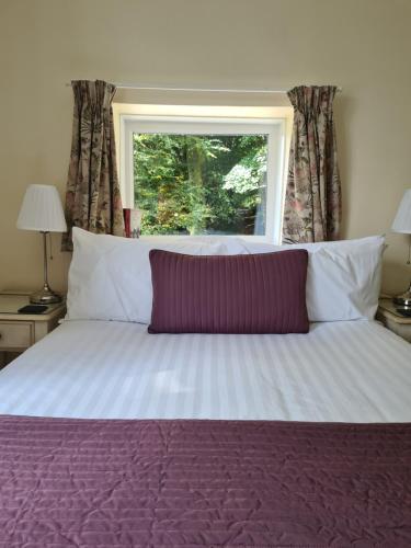 a bedroom with a large bed with a window at Lydgate House Hotel in Postbridge