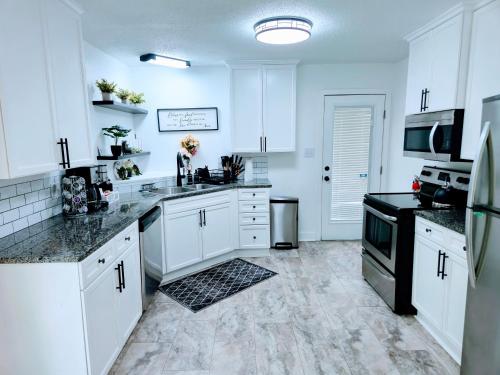 a white kitchen with white cabinets and black appliances at 2 Bedroom Kitchen and Living Area in Fayetteville