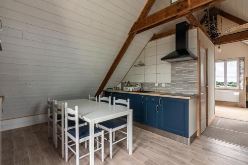 une cuisine avec des placards bleus et une table et des chaises blanches dans l'établissement hébergement Mézéozorn, à Plouguerneau