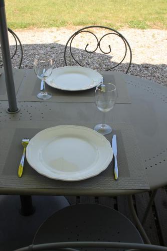 a table with two white plates and glasses on it at La Maison De Lena in Grézillac