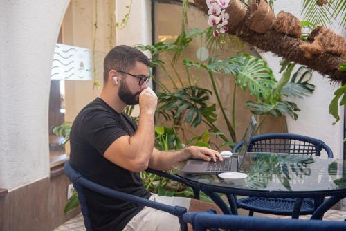 a man sitting at a table with a laptop computer at Opaba Praia Hotel in Ilhéus