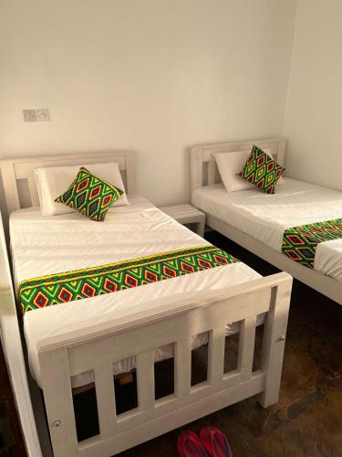 two twin beds in a room with red shoes at Kings and avana holiday villa in Watamu