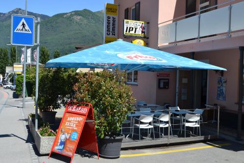 a table and chairs under a blue umbrella in front of a building at Osteria Centrale in Cadenazzo