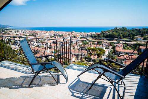 two chairs on a balcony with a view of the city at Hotel Indaco in Marina di Casalvelino