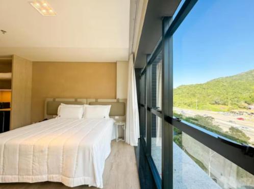 a bedroom with a bed and a large window at Hotel Blue Sea in Itapema