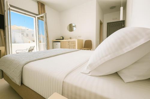 a white bedroom with a large bed with a window at Aqualis in Adamas