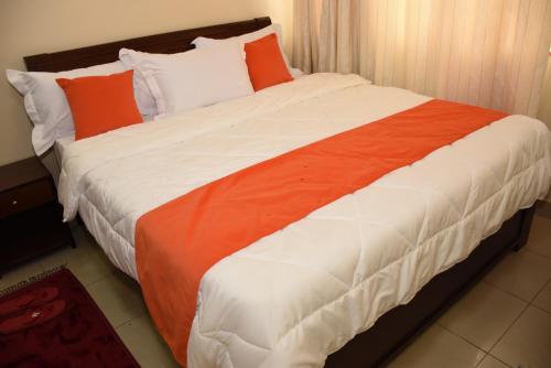 a large bed with orange and white sheets and pillows at Axis guest house in Nairobi
